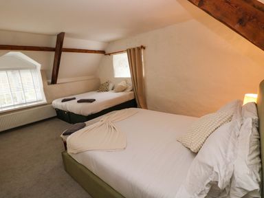 A bedroom with two beds a window and exposed wooden beams at Norchard Farm House Redberth near St Florence