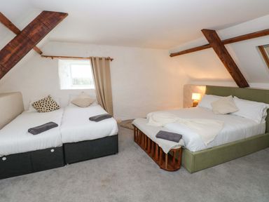 A bedroom with two beds pillows a lamp and wooden beams at Norchard Farm House Redberth near St Florence