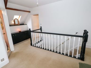 A landing area with a staircase railing and built-in cabinets under a skylight at Norchard Farm House in Redberth near St Florence