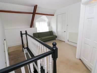 A landing area with a green sofa white doors and a staircase with black and white railings at Norchard Farm House Redberth near St Florence