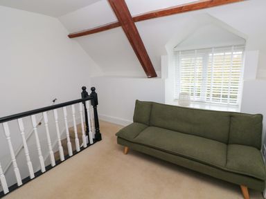 A small attic room with a green sofa near a window and a black and white banister at Norchard Farm House in Redberth near St Florence