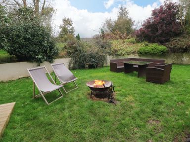A garden with two lounge chairs a fire pit and outdoor wicker furniture at Norchard Farm House in Redberth near St Florence