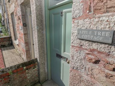 A green front door with number 5 and a sign reading apple tree cottage on a stone wall at Apple Tree Cottage in Gweek