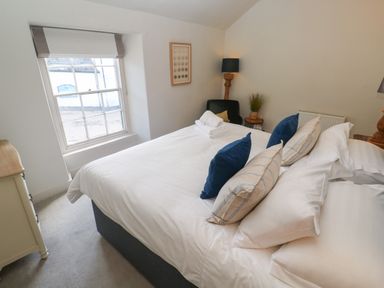 A bedroom with a bed and pillows next to a window at Apple Tree Cottage in Gweek