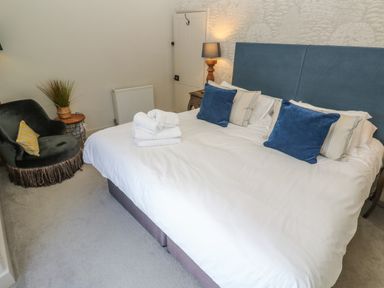 A bedroom with a bed a side table with a lamp a chair and folded towels at Apple Tree Cottage in Gweek