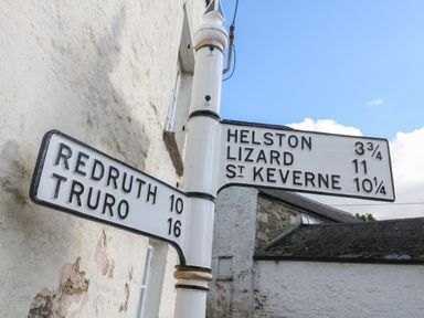 A street signpost with distances to Redruth Truro Helston Lizard and St Keverne with buildings in the background at Apple Tree Cottage in Gweek