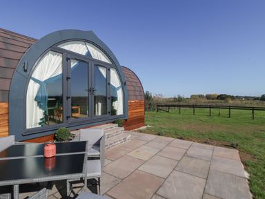 A patio with chairs and table outside a pod-shaped building at Leadon View Willow in Upleadon near Newent