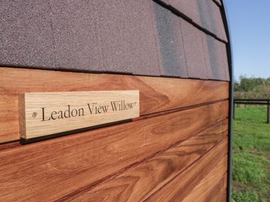 A wooden sign reading Leadon View Willow on a wooden exterior wall with a grassy field in the background at Leadon View Willow in Upleadon near Newent
