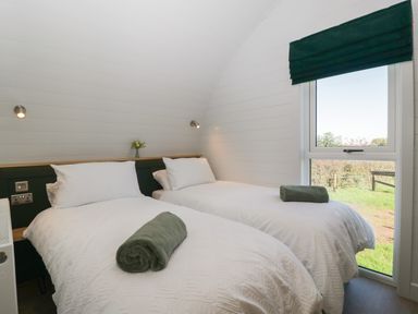 A bedroom with two single beds with rolled towels and a window with a green blind at Leadon View Willow in Upleadon near Newent