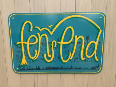A teal sign with yellow and green lettering that reads fen ster nd mounted on a wooden wall