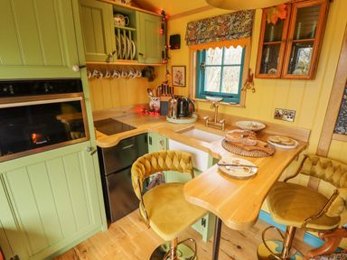 A kitchen with green cabinets yellow walls wooden countertops and two yellow bar stools at Catchwater in Keal Cotes near East Kirkby