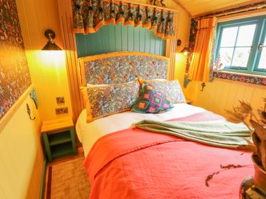 A bedroom with a double bed with floral headboard and pillows yellow walls and window curtains at Catchwater in Keal Cotes near East Kirkby