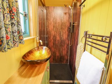 A bathroom with a copper sink wooden countertop glass shower enclosure and towel rack at Catchwater in Keal Cotes near East Kirkby