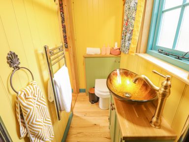A bathroom with a glass vessel sink a toilet towels and yellow walls at Catchwater in Keal Cotes near East Kirkby