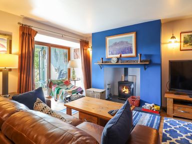A living room with a wood burning stove and blue accent wall at Hendre in Blaenau Ffestiniog