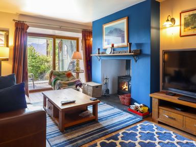 A living room with a blue accent wall fireplace wooden coffee table and television at Hendre in Blaenau Ffestiniog