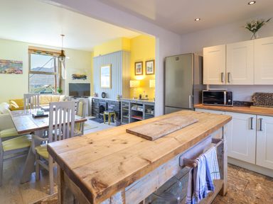 A kitchen with a wooden island and dining area with chairs and a sofa at Hendre in Blaenau Ffestiniog