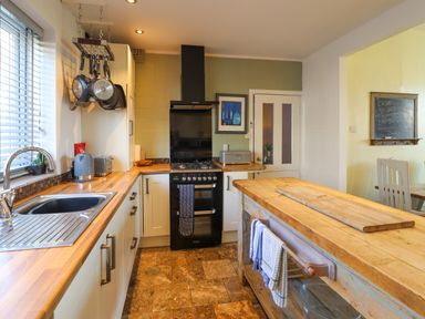 A kitchen with wooden countertops a black stove hanging pans and a wooden island at Hendre in Blaenau Ffestiniog