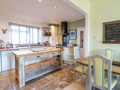 A kitchen with a wooden island and dining table with chairs at Hendre in Blaenau Ffestiniog