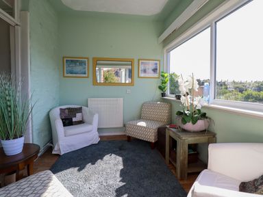 A sitting area with chairs a small table with plant a large window and pictures on the wall at Hendre in Blaenau Ffestiniog