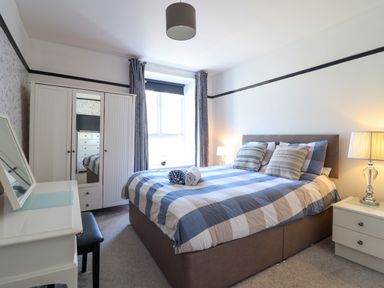A bedroom with a double bed bedside tables lamps a wardrobe and a dressing table at Hendre in Blaenau Ffestiniog