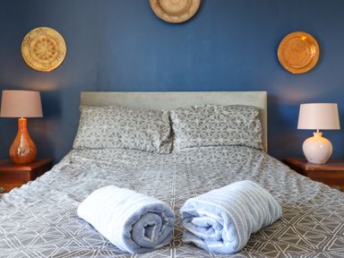 A bed with patterned bedding and two rolled towels on top with bedside tables and lamps at Hendre in Blaenau Ffestiniog