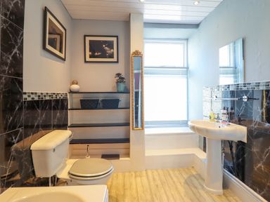 A bathroom with a toilet sink shelves and a window at Hendre in Blaenau Ffestiniog