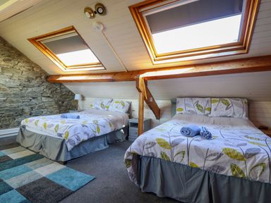 A bedroom with two double beds under skylights with leaf patterned bedding at Hendre in Blaenau Ffestiniog