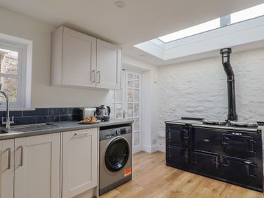 A kitchen with white cabinets a washing machine a black stove and a skylight at 47 Church Street in Lyme Regis