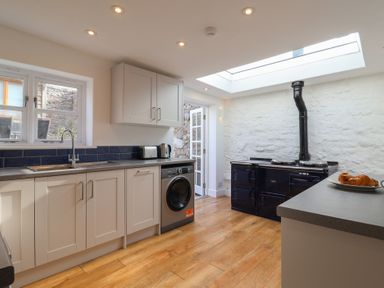 A kitchen with white cabinets a washing machine a black stove and a skylight at 47 Church Street Lyme Regis
