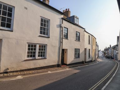 A narrow street with terraced houses and parked cars at 47 Church Street in Lyme Regis
