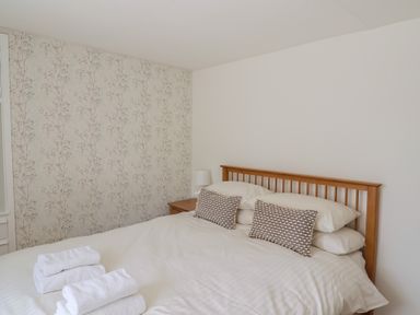 A bedroom with a double bed with folded towels on the bed and a bedside table with lamp at 47 Church Street in Lyme Regis