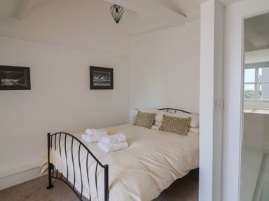 A bedroom with a double bed with folded towels on it and two framed pictures on the wall at 47 Church Street in Lyme Regis