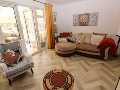 A living room with a round rug a sofa with cushions and a chair next to glass doors at Alban Road in Llanelli