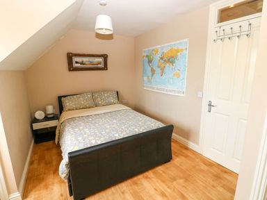 A bedroom with a bed a nightstand lamp world map on wall and a door at Alban Road in Llanelli
