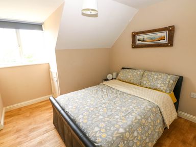 A bedroom with a double bed and floral bedding next to a window at Alban Road in Llanelli