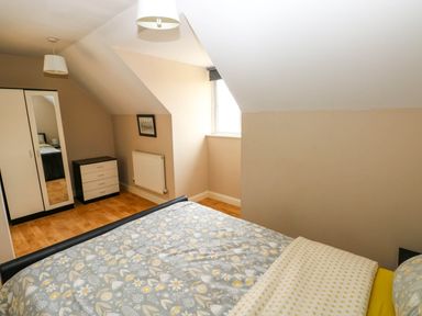 A bedroom with a bed wardrobe chest of drawers under a slanted ceiling at Alban Road in Llanelli