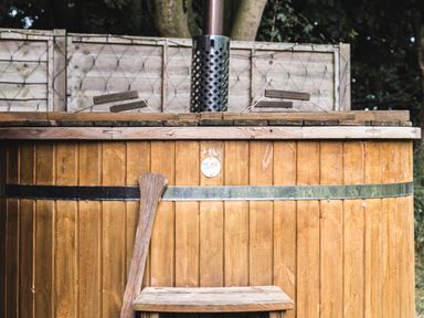 A wooden outdoor hot tub with lids and a wooden paddle at Little Otchan Shepherd's Hut in Halsham near Roos