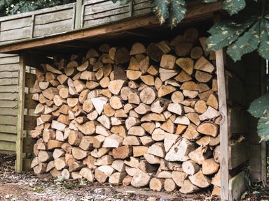 A stack of cut firewood stored under a wooden shelter at Little Otchan Shepherd's Hut in Halsham near Roos