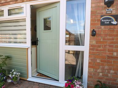 An entrance with a green door and plant decorations at Rainbow's End in Swanton Morley
