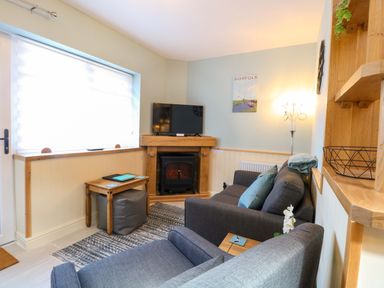 A living room with a television and sofa at Rainbow's End in Swanton Morley
