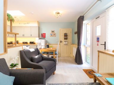 A kitchen with a sofa and dining area at Rainbow's End in Swanton Morley