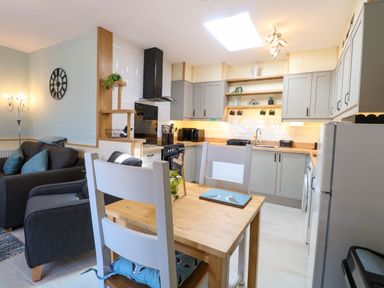 A kitchen with a sofa and dining table at Rainbow's End in Swanton Morley