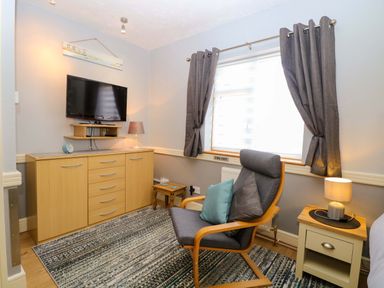 A bedroom with a television and an armchair at Rainbow's End in Swanton Morley