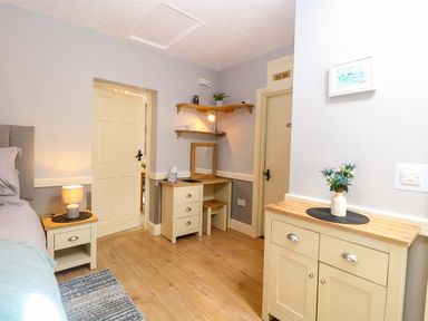 A bedroom with a bed, side table, desk and mirror at Rainbow's End in Swanton Morley