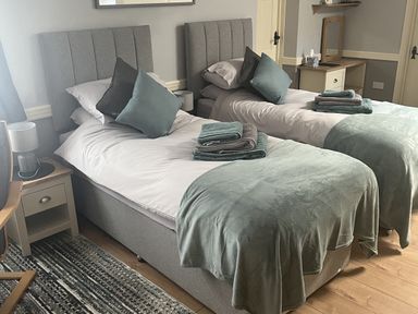 A bedroom with two single beds and a wooden chair at Rainbow's End in Swanton Morley