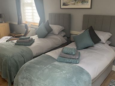 A bedroom with two beds and a chair at Rainbow's End in Swanton Morley