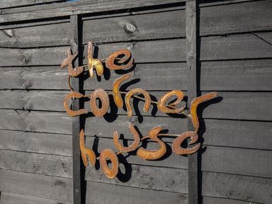 A rusty metal sign reading the corner house on a dark wooden fence at The Corner House in Ufford near Woodbridge