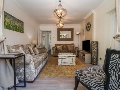 A living room with patterned sofas a wooden coffee table a television and a zebra print chair at The Corner House in Ufford near Woodbridge