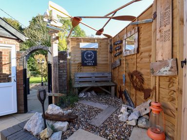 A garden seating area with wooden bench gravel and decorative signs at The Corner House in Ufford near Woodbridge